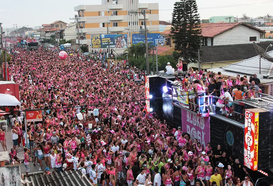 Multidão de rosa acompanhando o trio nas ruas de Laguna